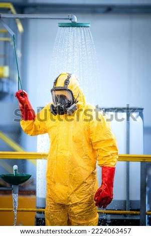 Chemical worker taking a shower and washing off aggressive chemicals after accident in acid production factory. Safety at work and workers health care. Royalty-Free Stock Photo #2224063457