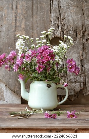 Aster flower bouquet in vintage jug on table on wooden background. Still living in a rustic style.
