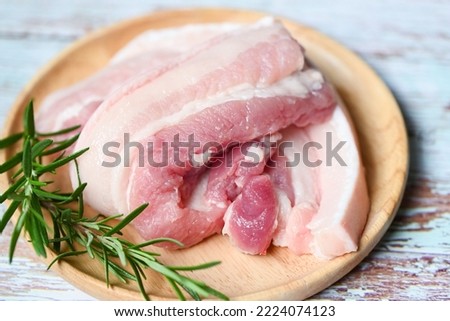 fresh raw streaky pork meat for cooking food, pork skin pig skin, pork on wooden plate with rosemary Royalty-Free Stock Photo #2224074123