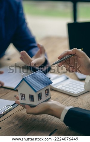 Real estate agents recommend homes and offer insurance interest rate contracts to clients in the home buying idea office.