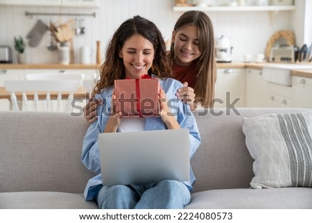 Teenage girl daughter giving birthday present to mom, child greeting congratulating mother on special occasion, smiling happy young woman receiving wrapped gift box with red bow from kid Royalty-Free Stock Photo #2224080573