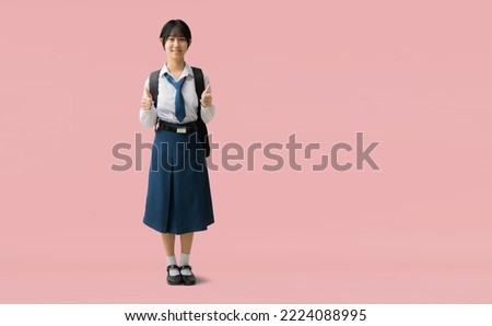 Full body Asian student girl wearing uniform with smiling giving thumbs up, isolated on pink background with Clipping paths for design work empty free space