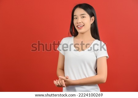 Portrait of Happy young asian woman in white t-shirt smiling and looking at camera isolated on red background. Expression and lifestyle concept.