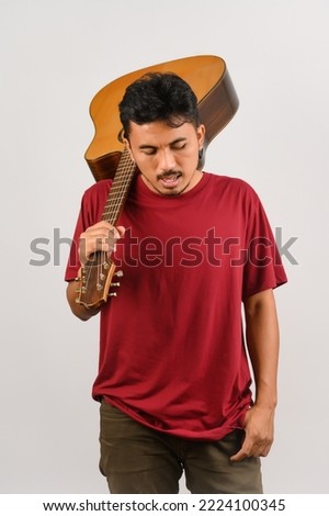 Portrait of Young Asian man in red t-shirt carrying an acoustic guitar isolated on white background. Music, entertainment and hobby concept.