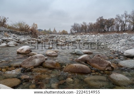 Slow and not deep mountain river with rounded stones
