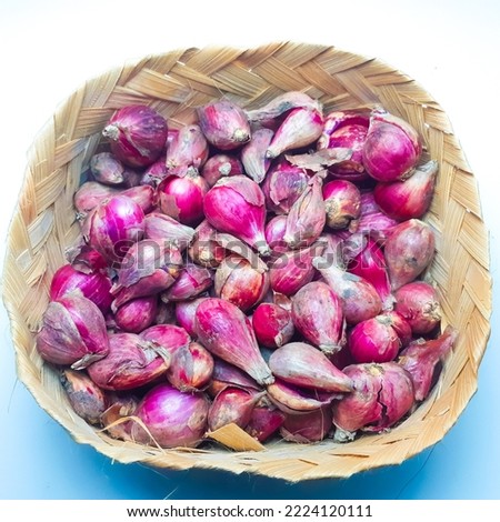 Top view of basket full of red onions in wooden basket, isolated white background