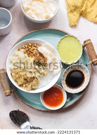 Bubur Ayam or Indonesian Rice Porridge with Shredded Chicken. Served with Kerupuk (Cracker), Soy Sauce, Fried Soy Bean, and Sambal Royalty-Free Stock Photo #2224131371