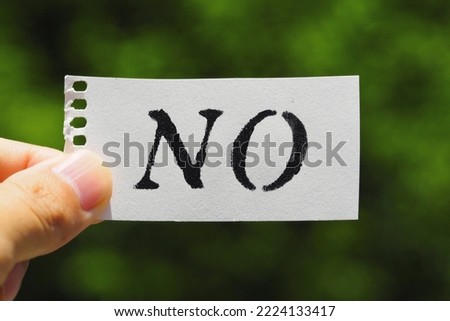 Person holding a piece of paper that says NO
