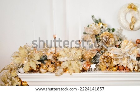 White and gold decoration of the Christmas fireplace with candles and a wreath