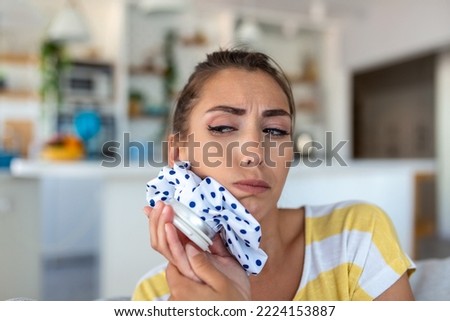 Portrait of young woman suffering from toothache, cooling her face with a ice pack Royalty-Free Stock Photo #2224153887