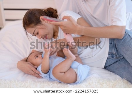 Mom happy feed milk to asian infant baby new born on bed father use mobile phone taking picture
