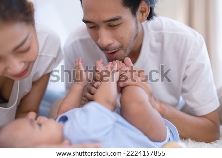 Mom and father happy joyful teasing asian infant baby new born have fun looking to parent face