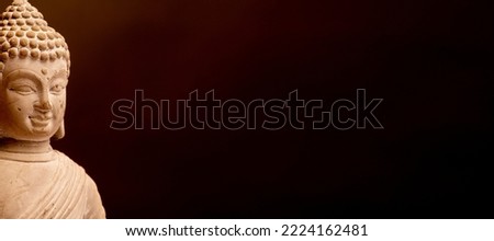 a buddha statue against a dark background with copy space