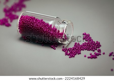 India, 8 November, 2022 : Beautiful glitter jar with pink color glitters still life background, wallpaper, backdrop. Purple glitters in a small glass bottle isolated on grey background.