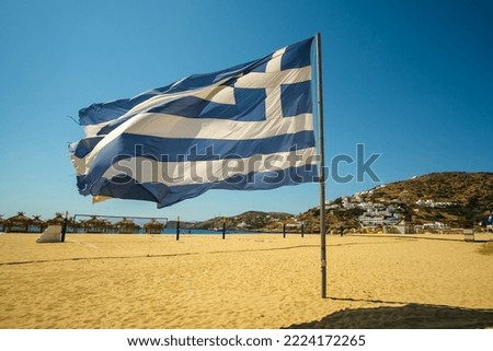 View of a beautiful big national greek flag blowing in the wind at the Mylopotas beach in Ios Greece