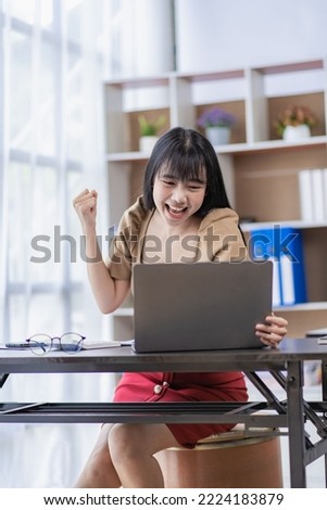 A young Asian businesswoman who is passionate and excited about her job and happily raises her hand for a successful business. vertical picture