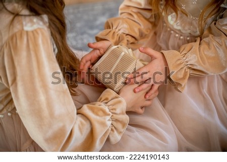 Close-up of a gift box in the hands of two girls. For birthday, Christmas and New Year. Family lifestyle, holiday celebration.