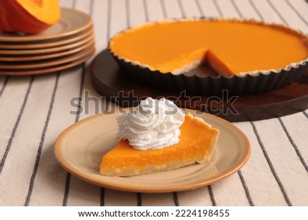 Piece of fresh homemade pumpkin pie with whipped cream on table