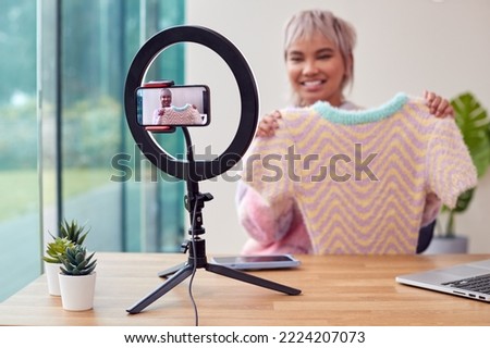 Female Vlogger Recording Fashion Or Clothing Product Review Video At Home With Mobile Phone