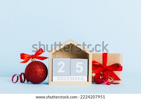 25 december. Christmas composition on colored background with a wooden calendar, with a gift box, toys, bauble copy space.