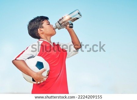 Training, sports and football with child drinking water for fitness, health or endurance exercise. Wellness, summer and workout with young soccer player and bottle for electrolytes, relax and thirsty Royalty-Free Stock Photo #2224209155
