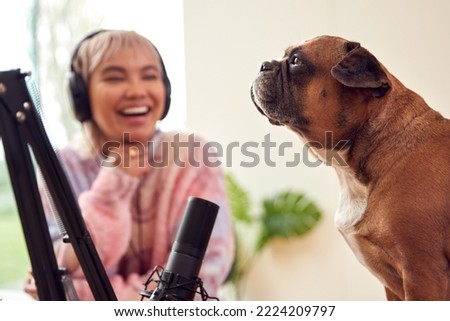 Woman With Pet French Bulldog Recording Podcast Or Broadcasting On Radio In Studio At Home