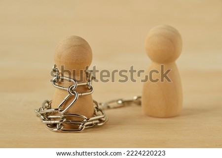Wooden pawn with chains controlled by his partner - Concept of toxic relationship, love, domination and control Royalty-Free Stock Photo #2224220223