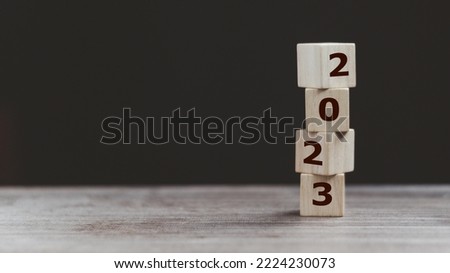 2023 Happy New year background banner. Two thousand Twenty-Three year numbers on wooden cube blocks stack on dark  background with copy space. Welcome, Merry Christmas, and Happy New Year in 2023. Royalty-Free Stock Photo #2224230073