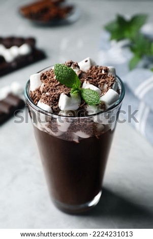 Glass of delicious hot chocolate with marshmallows and fresh mint on light grey table