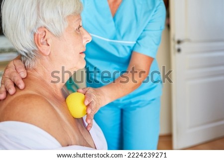Elderly woman gets a trigger point massage with a small massage ball in the physio