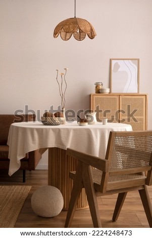 Minimalist composition of dining interior with round wooden table, design chair, pendant rattan lamp, vase with dried flowers, decoration and personal accessories. Stylish home decor. Template.	
 Royalty-Free Stock Photo #2224248473