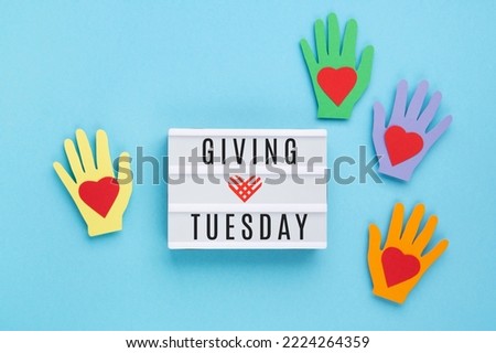Giving Tuesday, global day of charitable giving after Black Friday shopping day. Charity, give help, donations support concept. Colorful hands, white lightbox, red heart on blue background. 