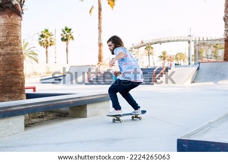 Side view of bearded skater riding before doing tricks in skate park