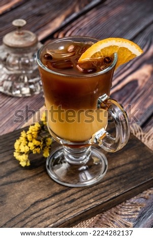 Glass of cocktail with orange juice and espresso coffee on wooden table. Iced orange espresso coffee