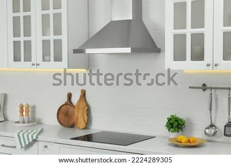 Elegant kitchen interior with modern range hood over cooktop and stylish furniture Royalty-Free Stock Photo #2224289305