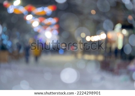 Blurred background. City street during snowfall at winter night. Many decorated Christmas trees, illumination, decoration on street. New Year Christmas holidays celebration. Lanterns garlands on trees