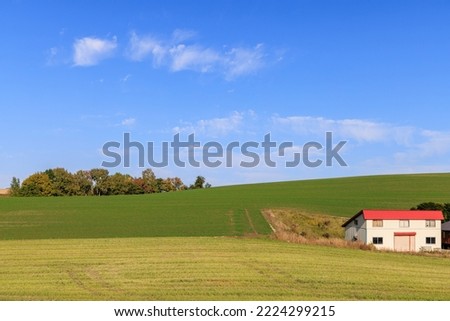 A red roof house on the green hills and blue sky Royalty-Free Stock Photo #2224299215