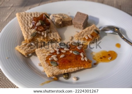 Healthy sandwich made from buckwheat crispbread, fresh honey and pumpkin and sunflower seeds on white plate.
