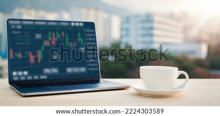 Close-up of laptop and coffee cup on the table with graphs, charts, diagrams on screen on table.Cityscape of background with Clipping Path of laptop screen.