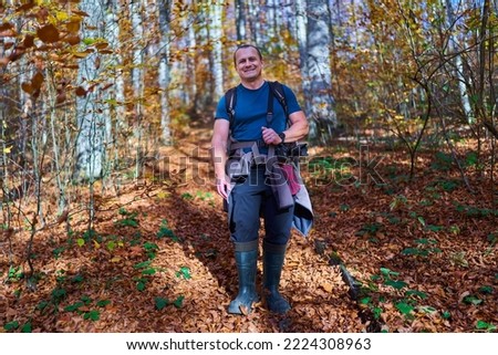 Nature photographer with heavy backpack hiking on a trail in the beech forest on mountain