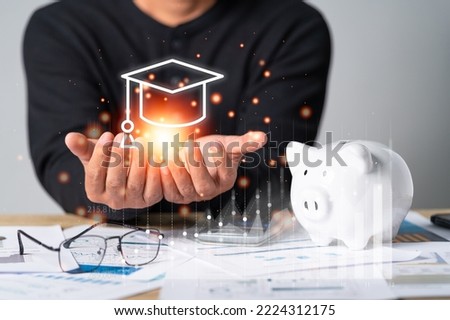 Businessman hand holding mortarboard icon with a piggy bank and business document, the concept for saving money, investment, tax, analyze economic, loan, income or salary
