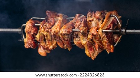 Czech Republic street food, piece of pork is cooked on grill spit with burn. Royalty-Free Stock Photo #2224326823