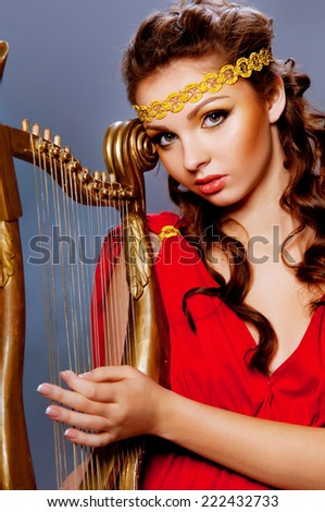 beautiful young woman in a Greek dress playing the harp