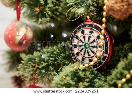 Close up picture of christmas ornaments on green artificial Xmas tree. Red and golden glass darts bauble, bead garland hanging on pine. Holiday atmosphere. New year celebration. Old decorations.