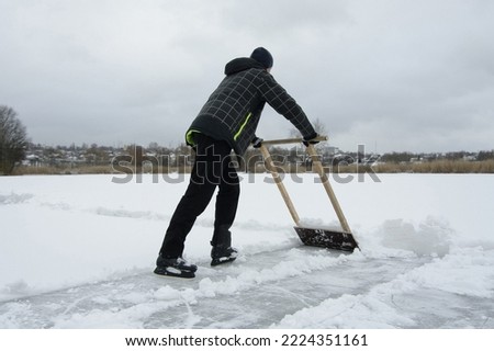 Preparing the field for playing hockey. A man on skates cleans the ice from snow. Close-up. Selective focus.