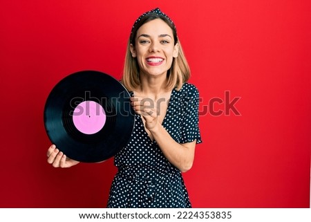 Young caucasian blonde woman holding vinyl disc smiling and laughing hard out loud because funny crazy joke. 