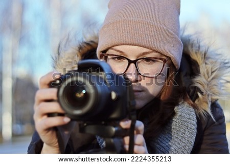 A girl with a SLR camera shoots landscapes focusing on the screen