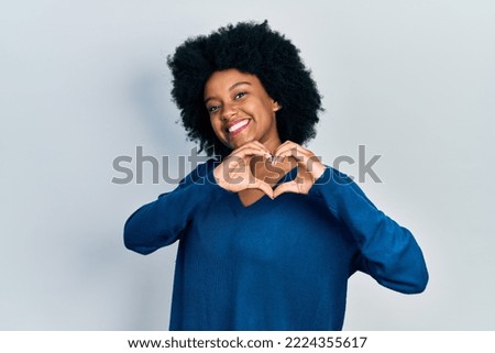 Young african american woman wearing casual clothes smiling in love doing heart symbol shape with hands. romantic concept.  Royalty-Free Stock Photo #2224355617