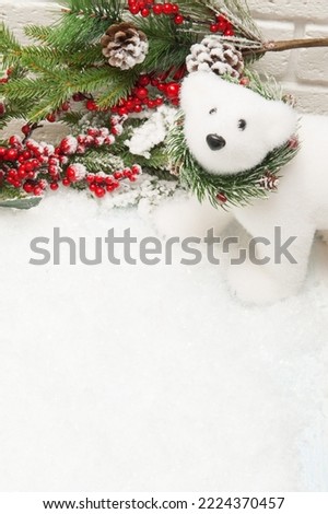 Christmas background White polar toy bear, branch with red berries and artificial snow