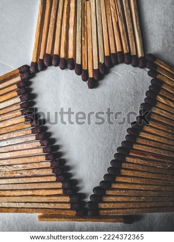 This a picture of heart which is made of matchsticks head. Matchsticks back are making a pattern.